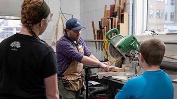 girl and boy watching woodshop demonstration